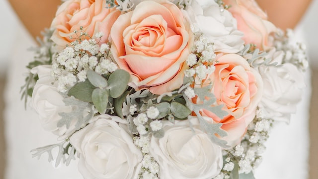 bridal bouquet with arms and wedding dress visible behind